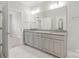 Well-lit bathroom featuring a double vanity with granite counters, gray cabinetry, and a large mirror at 6220 Raven Rock Dr, Denver, NC 28037