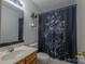 Compact bathroom featuring a wood vanity, mirror, and butterfly shower curtain at 6808 Squirrels Foot Ct, Charlotte, NC 28217