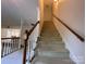 Carpeted staircase with wooden railings, offering a view into a spacious living area, seamlessly connecting floors at 944 Evian Ln, Matthews, NC 28015