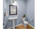 Powder bathroom with blue walls, wood floors, and pedestal sink at 10517 Sable Cap Rd, Mint Hill, NC 28227