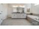 Bright bathroom with dual sinks, granite countertops, tiled floors, and a soaking tub at 1107 Castle Rd, Indian Land, SC 29707