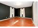 A bedroom featuring dark-colored walls and red-toned wood floors, illuminated by two windows with bright light at 1108 Old Dallas Hwy, Dallas, NC 28034