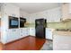 Well-lit kitchen featuring white cabinets, black appliances, laminate wood floors, and a clean design at 1108 Old Dallas Hwy, Dallas, NC 28034