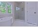 Modern bathroom boasting a soaking tub, glass enclosed shower with niche, and a large window at 116 S Broad St, Waxhaw, NC 28173
