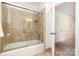 Tiled shower over tub with sliding doors and adjacent hallway access with white trim at 1209 Alfred St, Charlotte, NC 28211