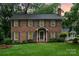 Traditional two-story brick home with dark shutters, mature landscaping, and green lawn at 1209 Alfred St, Charlotte, NC 28211
