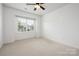 Bright, carpeted bedroom with a ceiling fan and large window, offering a comfortable and inviting atmosphere at 14210 Asbury Park Rd, Huntersville, NC 28078