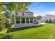 View of the home's manicured backyard, enclosed sunroom, outdoor kitchen, and mature trees at 150 Pleasant Grove Ln, Mooresville, NC 28115