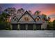 Detached four-car garage with stone facade and sunset sky creates an inviting and unique exterior at 172 Tennessee Cir, Mooresville, NC 28117