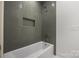 Well-lit bathroom with a modern tub, stylish gray tiling, and convenient storage niche at 1817 Union St, Charlotte, NC 28205