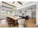 View of dining room with large table, wood beams, and modern light fixture open to the contemporary kitchen space at 1817 Union St, Charlotte, NC 28205