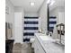 Bathroom features a large vanity, mirror, cabinet, toilet and shower with striped curtain at 208 Wellington Dr, Lincolnton, NC 28092