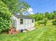 White backyard shed with double doors, surrounded by lush greenery and a clear blue sky at 208 Wellington Dr, Lincolnton, NC 28092
