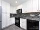 This modern kitchen features black appliances, white cabinets, a black and white backsplash, and granite countertops at 2502 Breuster Dr, Charlotte, NC 28210