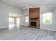 Bright living room featuring a brick fireplace and large windows with modern, gray flooring at 2502 Breuster Dr, Charlotte, NC 28210