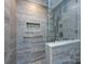 Modern bathroom shower with gray tiling, glass surround, built-in niche, and pebble floor at 2502 Breuster Dr, Charlotte, NC 28210
