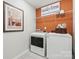 Functional laundry room with modern washer and dryer, ample shelving, and bright orange walls at 2585 Blue Sky Meadows Dr, Monroe, NC 28110