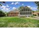 Exterior view displaying the home's backyard, lush lawn, patio area, and a sunroom with expansive windows at 2626 Lilly Mill Rd, Charlotte, NC 28210
