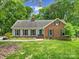 Charming home with a lush green lawn, mature trees, and a mix of brick and siding exterior at 2626 Lilly Mill Rd, Charlotte, NC 28210