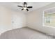 Bright bedroom featuring neutral carpet, ceiling fan, and ample natural light from the window at 2638 Double Oaks Rd, Charlotte, NC 28206