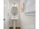 Charming powder room with pedestal sink, decorative mirror, and ample natural light at 2638 Double Oaks Rd, Charlotte, NC 28206