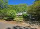 Exterior view of a house surrounded by trees, featuring a driveway and a car parked near the house at 3712 Avalon Ave, Charlotte, NC 28208