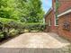 A stone patio is nestled in the lush backyard of this red brick home, providing an outdoor living space at 3904 Hounslow Ln, Harrisburg, NC 28075