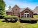 Exterior of a 2-story red brick home featuring lush greenery and manicured landscaping at 3904 Hounslow Ln, Harrisburg, NC 28075