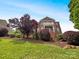 Two-story brick home with a balcony, beautiful landscaping, and healthy trees on a lush green lawn at 3904 Hounslow Ln, Harrisburg, NC 28075
