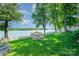 Green backyard featuring mature trees, a fire pit, a boat dock and lake views, and a white picket fence at 4960 Longfield St, Claremont, NC 28610