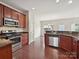 Stainless steel appliances and cherry cabinets in kitchen featuring hardwood floors at 5355 Hackberry Sw Ln, Concord, NC 28027