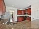 Well-lit kitchen featuring granite counters, stainless steel appliances, and cherry cabinets at 5355 Hackberry Sw Ln, Concord, NC 28027