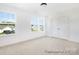 Bright bedroom featuring neutral carpet, closet and two windows with street view at 5594-C Galloway Dr # 99P, Stanfield, NC 28163