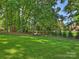 Large grassy backyard with landscaping, lush trees, and a shed at 5917 Summerston Pl, Charlotte, NC 28277