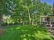 Large grassy backyard with a tree swing, mature trees, landscaping, and shed at 5917 Summerston Pl, Charlotte, NC 28277