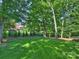 View of the lush backyard with a spacious lawn, mature trees, a shed, and a tree swing at 5917 Summerston Pl, Charlotte, NC 28277