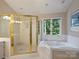 Large bathroom features a glass shower enclosure, soaking tub, and window overlooking trees at 5917 Summerston Pl, Charlotte, NC 28277