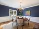 This dining area has dark blue walls, crown molding, a modern chandelier, and light-colored seating for six at 5917 Summerston Pl, Charlotte, NC 28277