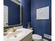 Stylish half bathroom offers a designer's mirror and blue painted walls at 5917 Summerston Pl, Charlotte, NC 28277