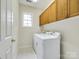 Well-lit laundry area featuring modern appliances, upper wood cabinets, and neutral walls at 720 Kingsmill Ln, Clover, SC 29710