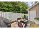 A cozy backyard patio space with outdoor furniture, a grill, a white fence, and greenery at 8259 Carob Tree Ln, Charlotte, NC 28215