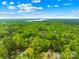 Expansive aerial view of a secluded estate surrounded by lush green forest and a glimpse of a tranquil lake at 8451 Ridgewood Rd, Sherrills Ford, NC 28673