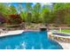 Inviting backyard pool and spa with lush landscaping, stone waterfall feature, and surrounding greenery at 8451 Ridgewood Rd, Sherrills Ford, NC 28673