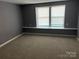 Well-lit bedroom with neutral carpet, gray walls, and a large window offering ample natural light at 9325 Old Concord Rd # D, Charlotte, NC 28213