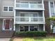 Three-story condo featuring two balconies with white cross-beamed railings, complemented by red brick and gray siding at 9325 Old Concord Rd # D, Charlotte, NC 28213