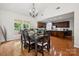 Dining room open to kitchen with hardwood floors, chandelier, and large windows at 109 Braxton Gate Ct, Mount Holly, NC 28120