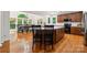 Open-concept kitchen and dining area with hardwood floors, dark wood cabinetry, and natural light at 109 Braxton Gate Ct, Mount Holly, NC 28120