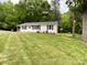 Front of the house with a sloping lawn, classic design, and lush surrounding greenery at 1105 S Church S St, Monroe, NC 28112