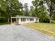 View of the home's front exterior highlighting the gravel driveway and the freshly manicured lawn at 1105 S Church S St, Monroe, NC 28112