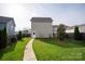 Green backyard with a walkway leading to a detached garage at 13818 Jacks Ln, Pineville, NC 28134